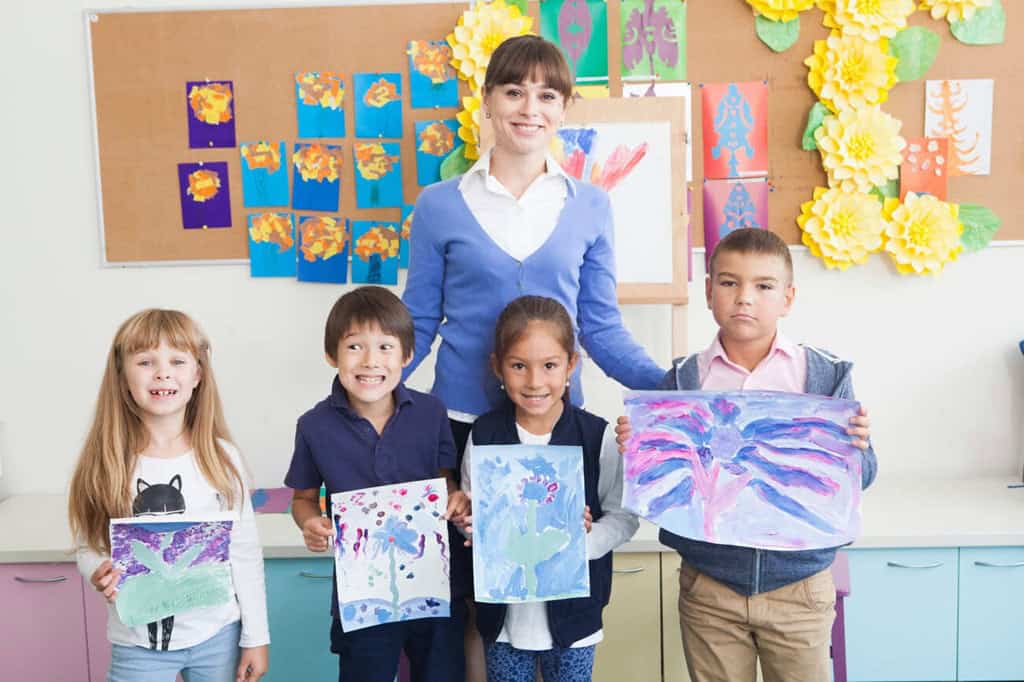 授業で描いた絵を見せる先生と子どもたち