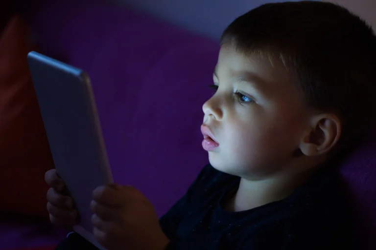 Child using a tablet in a dark room showing the impact of screen time on brain development